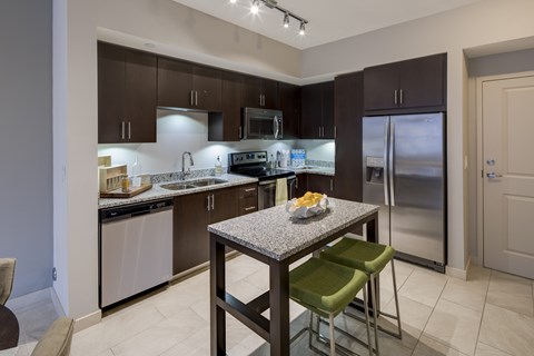 A kitchen with a table and chairs in front of a refrigerator.