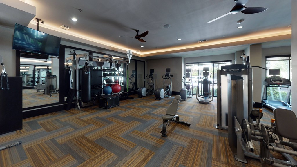 a spacious fitness room with cardio equipment and a flat screen tv