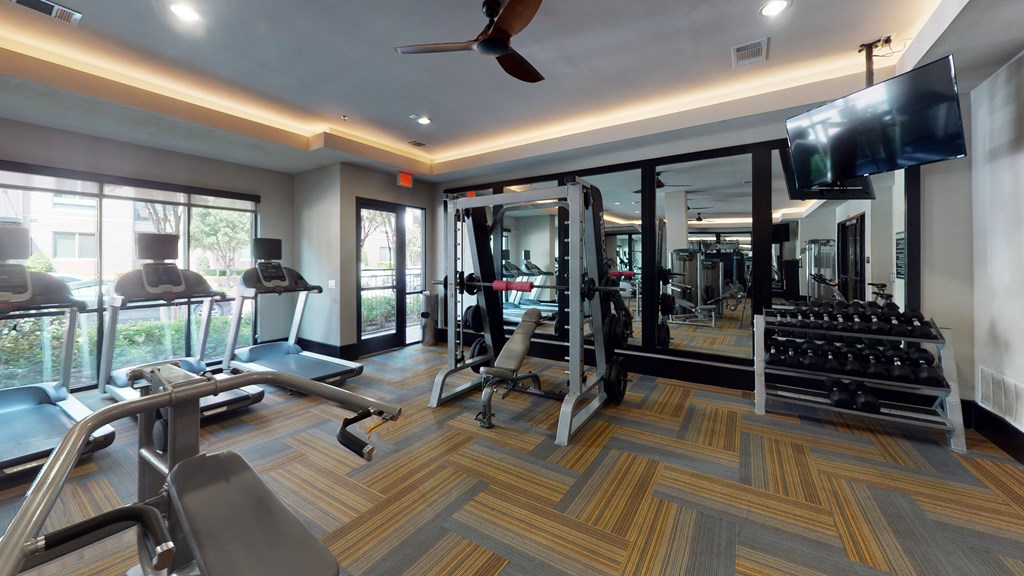 a gym with cardio equipment and a flat screen tv