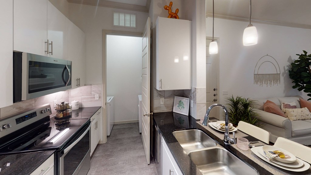 a kitchen with white cabinets and black countertops