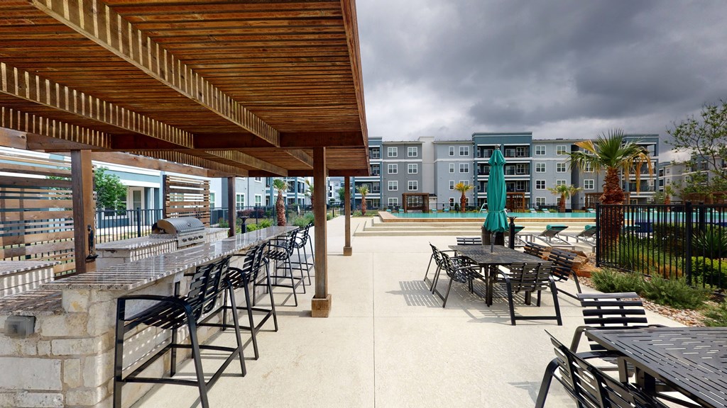 a patio with tables and chairs and a pool in the background