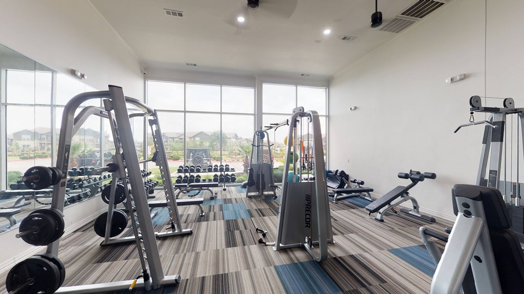 a gym with a lot of exercise equipment on the floor and a large window