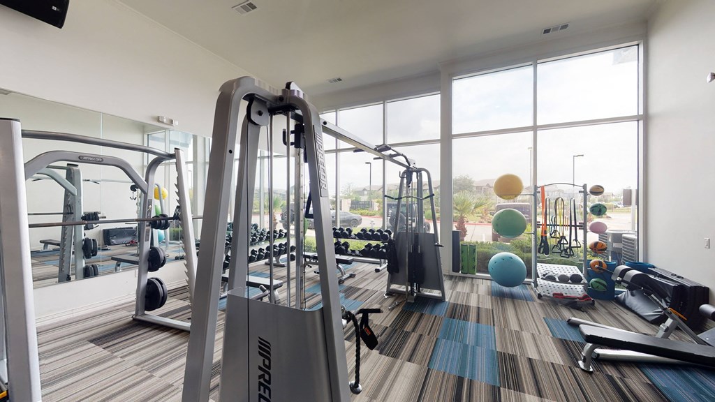 a gym with a lot of exercise equipment and large windows