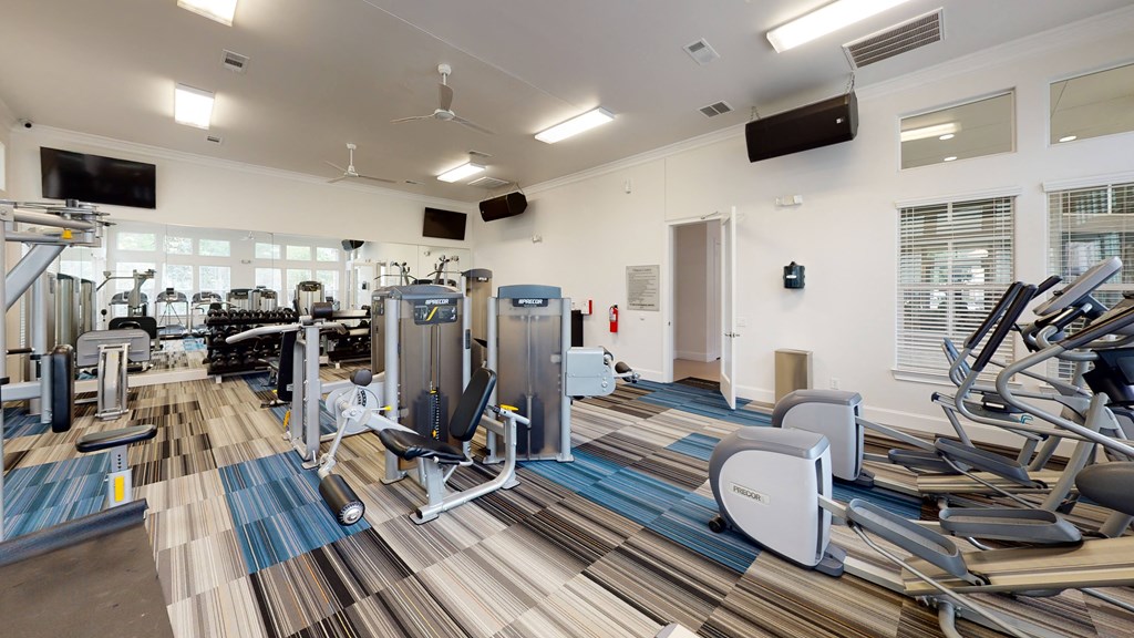 a spacious fitness center with cardio equipment and a flat screen tv