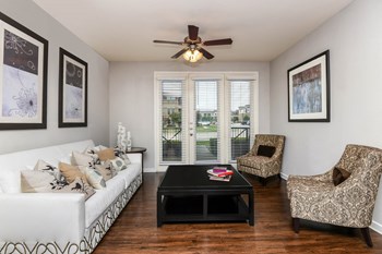 Soho Parkway apartments living room with ceiling fan and hardwood-inspired flooring - Photo Gallery 8
