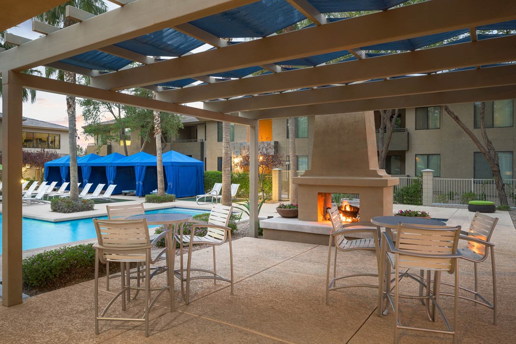 Outdoor fireplace with pergola next to pool