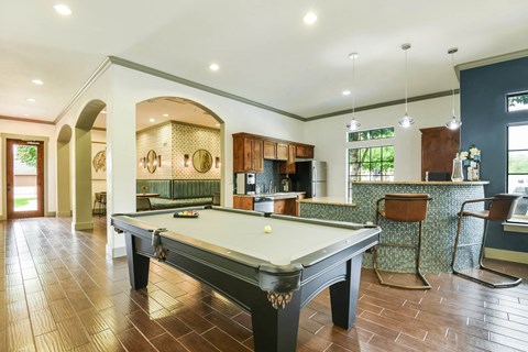 a pool table in a living room with a kitchen