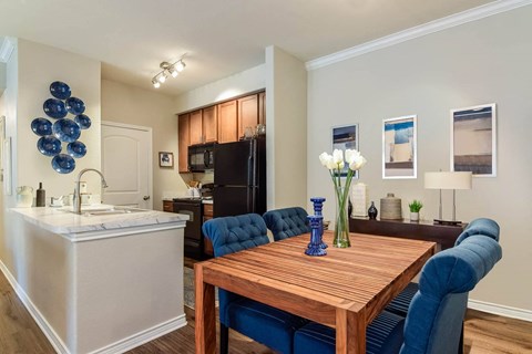 a dining room table with blue chairs next to a kitchen