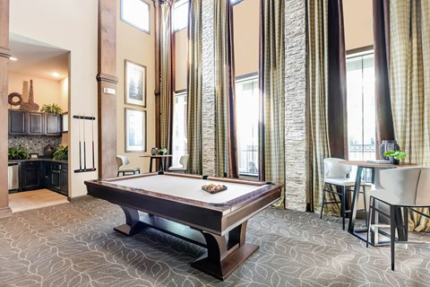 a billiards table in a clubhouse with a dining area and a kitchen