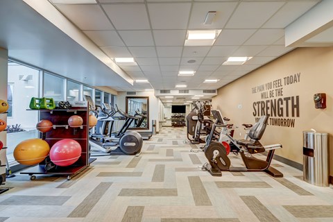 A gym with a variety of equipment and a motivational quote on the wall.