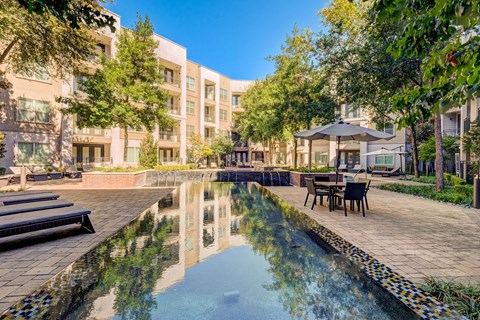 A pool in the middle of a courtyard surrounded by buildings and trees.