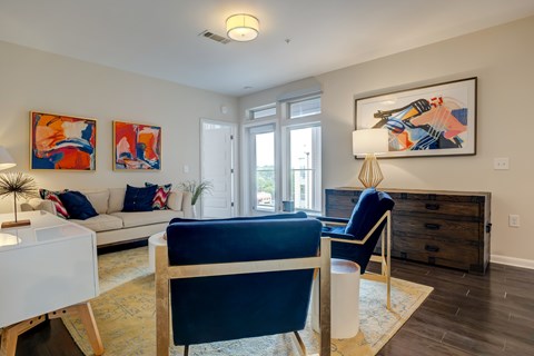 A living room with a blue chair and a painting on the wall.