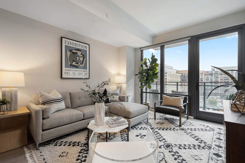 an open living room with a couch and large windows in Tribeca NOMA apartments