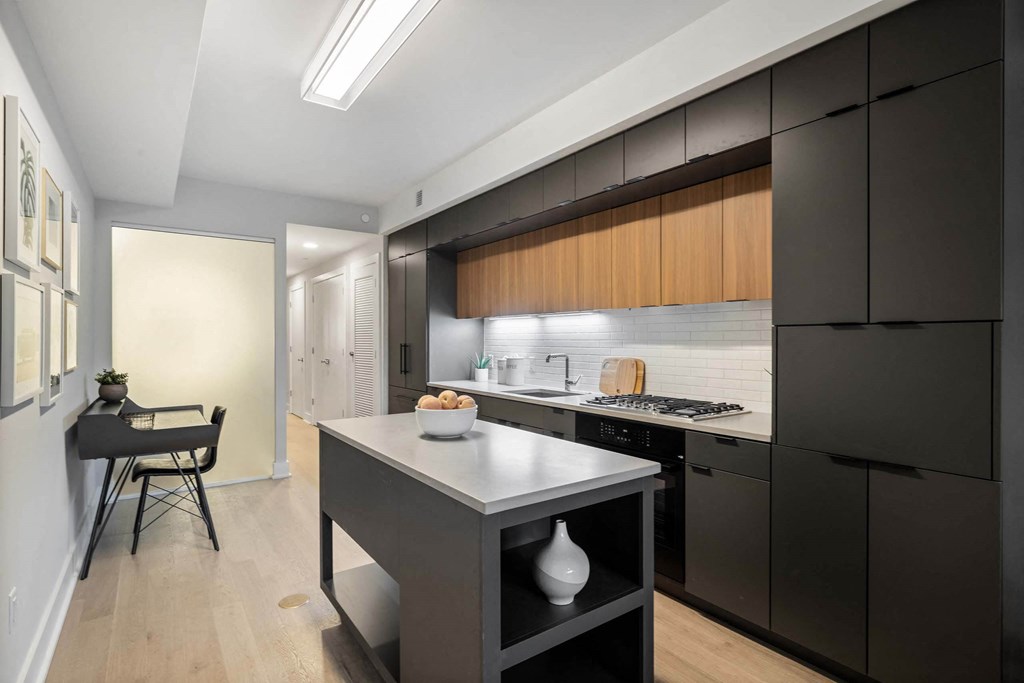 a modern kitchen with black cabinets and white countertop at Tribeca NOMA apartments