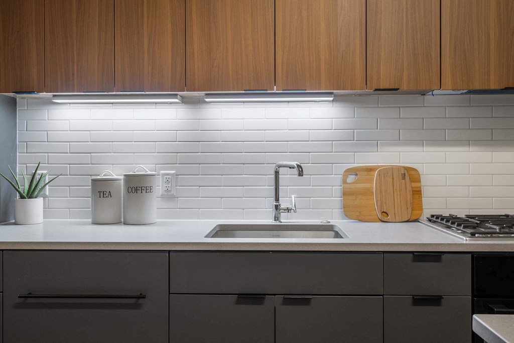 A white kitchen counter with a sink and wooden cabinets at Tribeca NOMA apartments