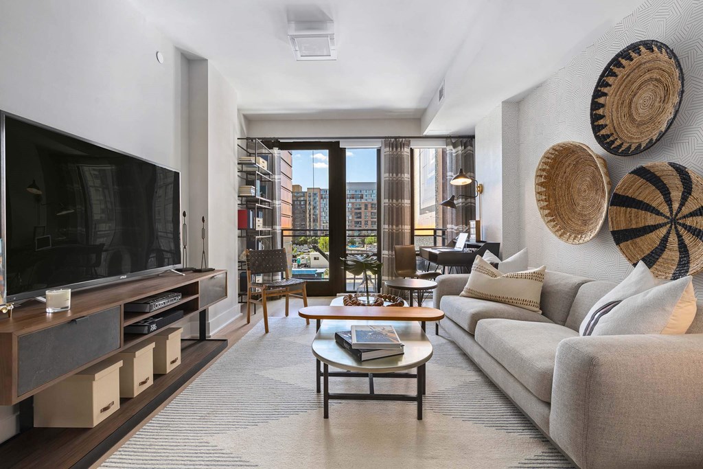a living room with a couch and a tv and a balcony at Tribeca NOMA apartments
