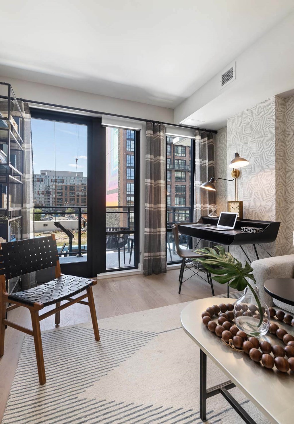a living room with a black desk and a view of a balcony at Tribeca NOMA apartments