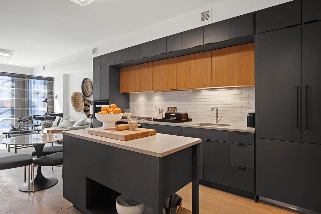 a kitchen with black cabinets and a counter with a bowl of fruit at Tribeca NOMA apartments