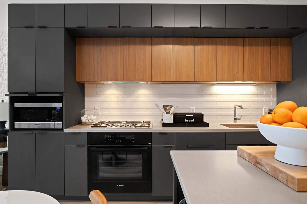 a kitchen with black wooded cabinets and sleek appliances at Tribeca NOMA apartments