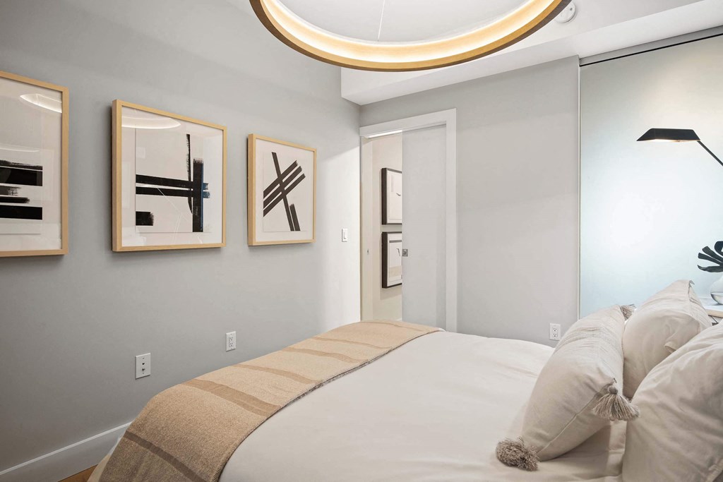 a bedroom with a bed and modern light fixture at Tribeca NOMA apartments