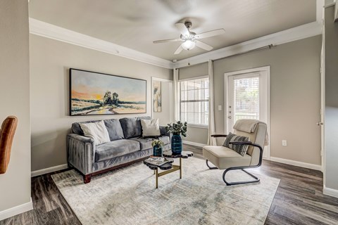 A living room with a grey couch, a chair, and a painting on the wall.