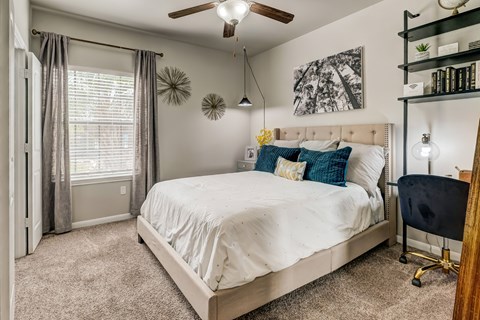 A bedroom with a large bed and a ceiling fan.