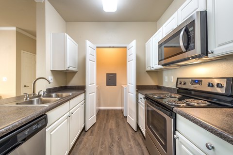 A kitchen with white cabinets and black appliances.