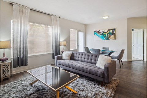 A modern living room with a grey sofa and a glass coffee table.