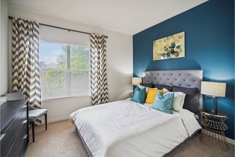 A bedroom with a large bed and a window with curtains.