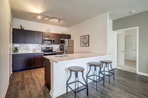 A kitchen with a white counter and bar stools.