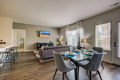 A modern dining room with a glass table and grey chairs.