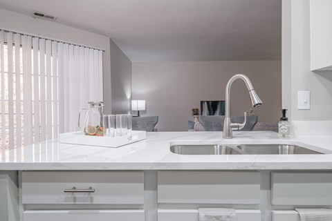 A modern kitchen with a white countertop and a stainless steel sink.