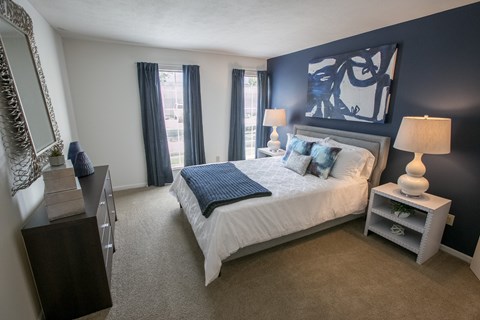 A bedroom with a large bed and a nightstand with a lamp.