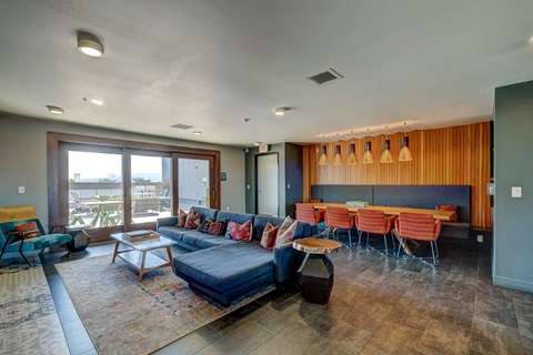 A living room with a blue couch and a dining table with chairs.