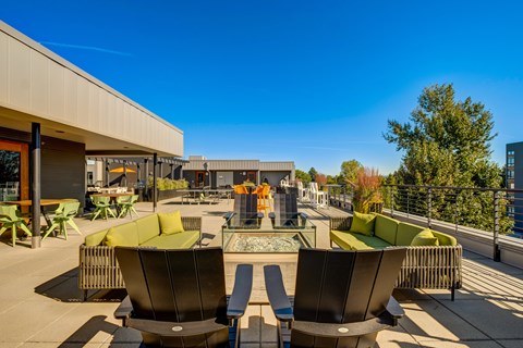 A sunny day at a modern outdoor seating area with green couches and tables.