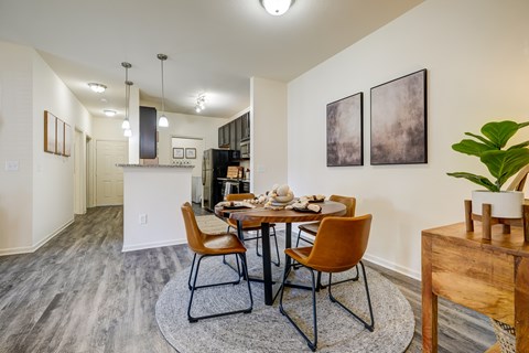 A dining room with a table set for two and a plant on the side table.