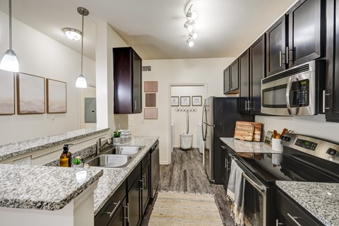 A kitchen with black cabinets and granite countertops.