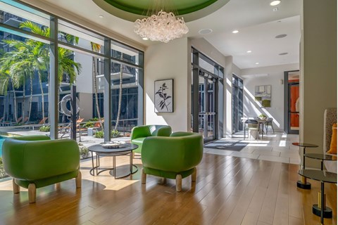 a living room with green chairs and a chandelier