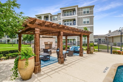 A large patio area with a wooden pergola and a pool.