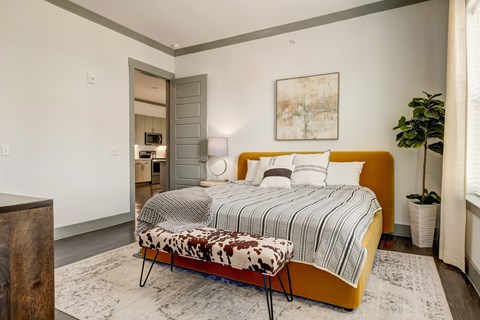 A bedroom with a bed, a chair, and a potted plant.