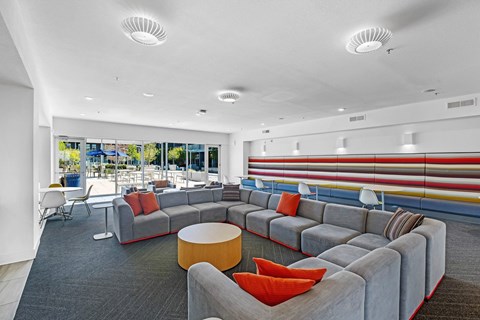 A modern living room with grey couches and red pillows.