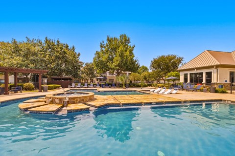 A large outdoor swimming pool with a wooden deck and sun loungers.