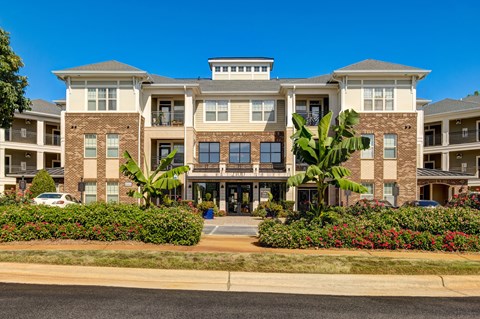 A large apartment building with a front yard and landscaping.