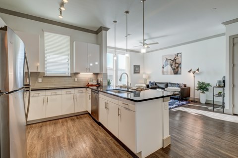 A modern kitchen with white cabinets and a wooden floor.