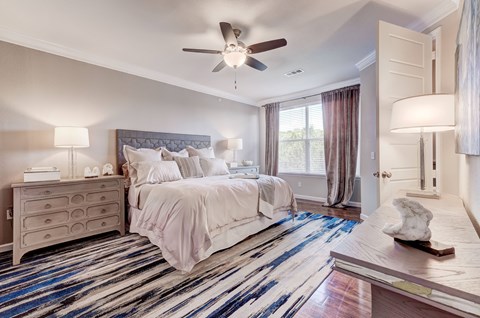 A bedroom with a large bed and a ceiling fan.