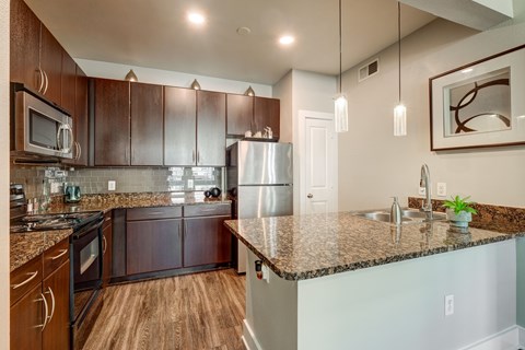 A kitchen with brown cabinets and a granite countertop.