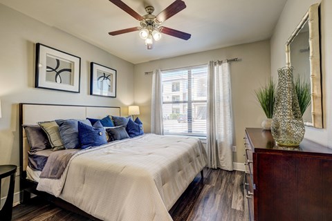 A bedroom with a bed, a dresser, and a ceiling fan.