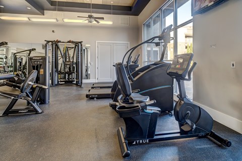 A gym with a variety of exercise equipment including treadmills, elliptical machines, and weight machines.
