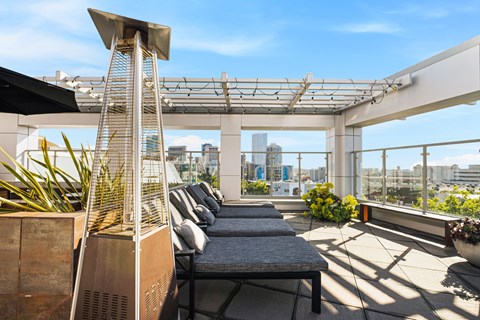 A rooftop patio with a couch, plants, and a city view.