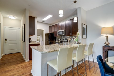 A kitchen with a marble island and white chairs.